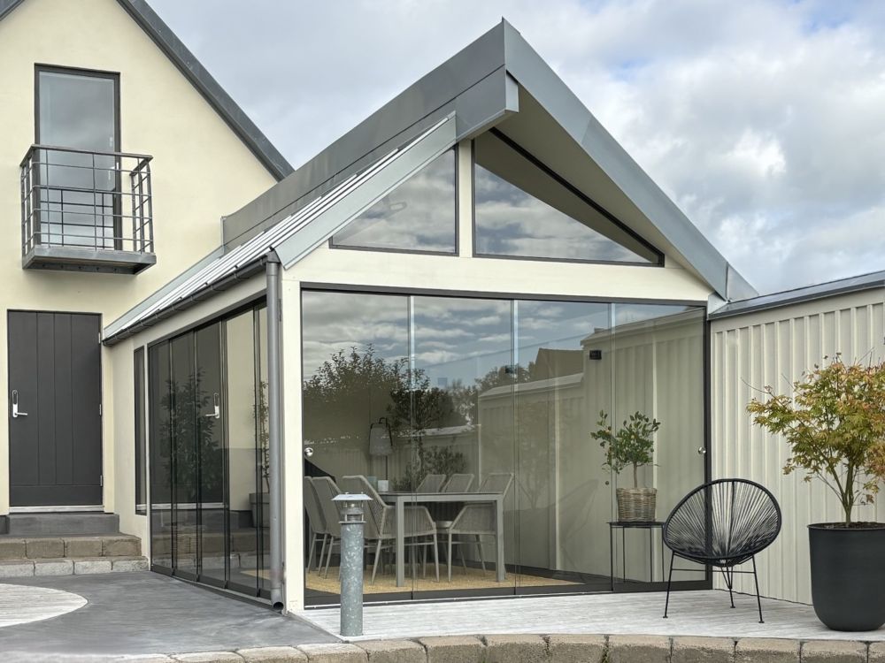 Modernt uterum med ramlösa skjutpartier som skapar en ljus och öppen övergång mellan huset och uteplatsen. | Panorama M20 glaspartier | Mekoflex Uterum