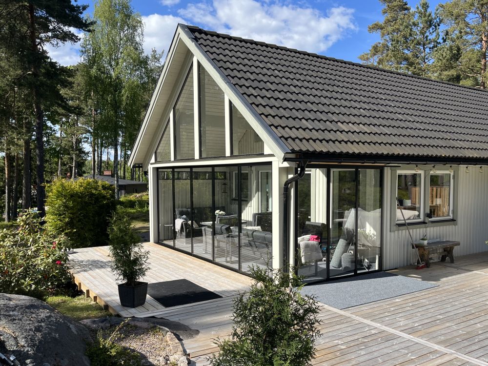 Modernt uterum med svarta glaspartier och trädäck. Ett exempel på hur glaspartier kan anpassas efter uterummets öppningar för ett genomtänkt slutresultat. | Sommar M50 glaspartier | Mekoflex Uterum