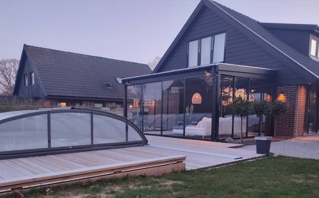 Fasadmonterat uterum med stora glaspartier och skjutdörrar, anslutet till ett modernt hus. | Mekoflex Uterum