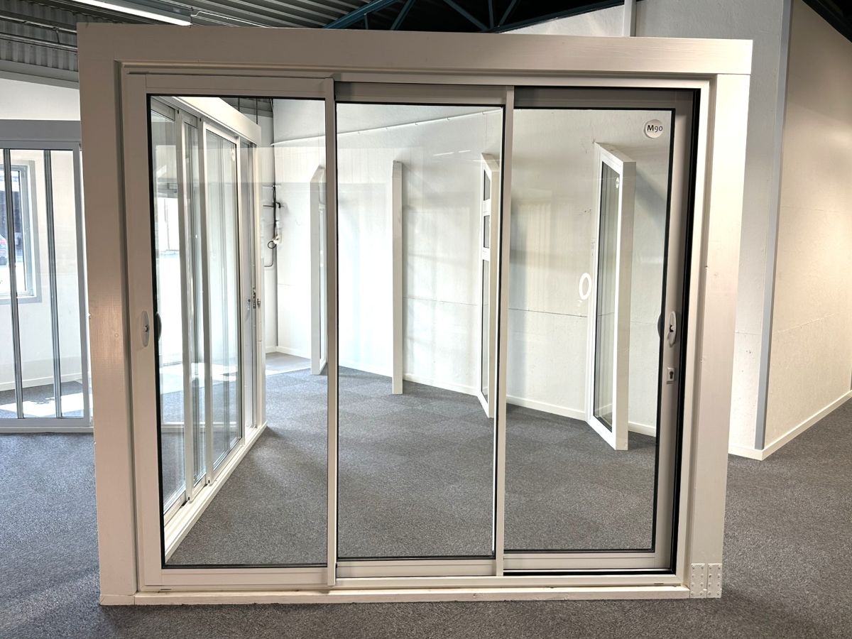 3-delat skjutparti i aluminium med isolerglas och integrerat lås med nyckel, visat i en utställningshall. Skjutpartiet är måttanpassat och lämpligt för vinterträdgårdar.