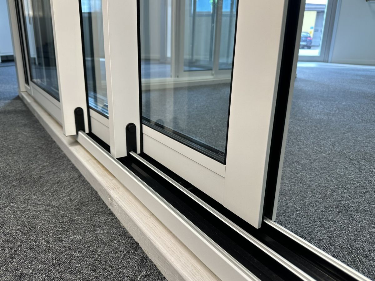 Närbild på ramprofil och isolerade skjutdörrar med bruten köldbrygga som löper smidigt på en räls.